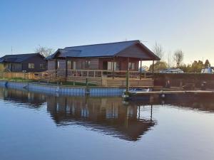 a house on a dock next to a body of water at River Bay - Norfolk Broads in Brundall