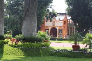 ein orangefarbenes und weißes Haus mit Bäumen und Blumen in der Unterkunft Hotel La Villa Real in Cuautla Morelos