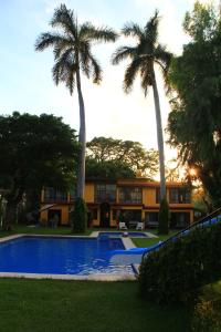 a house with a swimming pool and two palm trees at Hotel La Villa Real in Cuautla Morelos