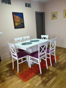 einen weißen Esstisch mit 4 Stühlen und einem Teppich in der Unterkunft Studio Bauhaus in Čačak