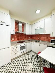 a kitchen with white cabinets and a black and white tile floor at Casa dos Cantares in Padrón