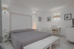 a white bedroom with a bed and a table at The Pelican Beach Resort & SPA - Adults Only in Olbia