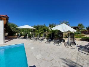 a row of chairs and umbrellas next to a swimming pool at Pranjic Delux Guest House in Vodice