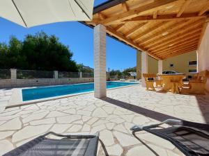 a patio with a swimming pool and a wooden pergola at Pranjic Delux Guest House in Vodice