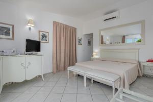 a white bedroom with a bed and a mirror at The Pelican Beach Resort & SPA - Adults Only in Olbia