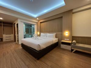 Un dormitorio con una cama grande y un banco. en เดอะสแควร์โฮเทลนครพนม en Nakhon Phanom