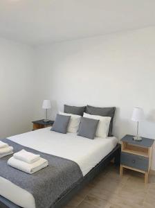 um quarto com uma grande cama branca e duas mesas em Summer Reference em Tavira
