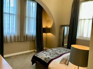 a bedroom with a bed and a mirror and a lamp at Quebecs Luxury Apartments in Leeds