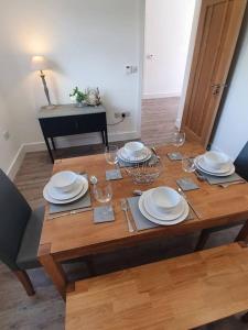 a wooden table with plates and wine glasses on it at Beech Cottage in Rothbury