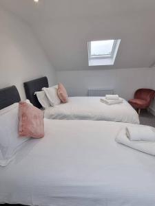 two white beds in a room with a window at Copper Cottage in Rothbury