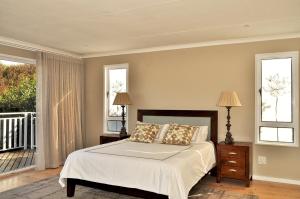 a bedroom with a bed and two windows at Glentana Beach Rental in Groot Brak Rivier