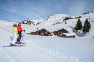 duas pessoas em esquis na neve perto de um alojamento de turismo selvagem em Apartment 1919 em Kitzbühel