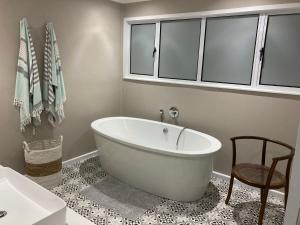 een badkamer met een groot wit bad en een stoel bij Glentana Beach Rental in Groot Brak Rivier
