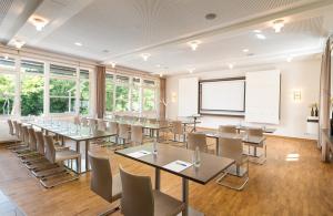 a conference room with tables and chairs and a whiteboard at Flussbett Hotel in Gütersloh
