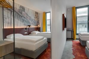 a hotel room with two beds and a tv at Campanile Muenchen Sendling in Munich