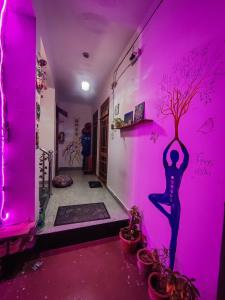 ein Zimmer mit einer rosa Wand mit einem Baum an der Wand in der Unterkunft Space house hostel in Rishikesh