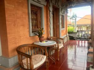 un tavolo e sedie sul portico di una casa di Puri Mandala Kaleran ad Ubud