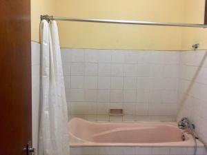 a bathroom with a pink bath tub with a shower curtain at Puri Mandala Kaleran in Ubud