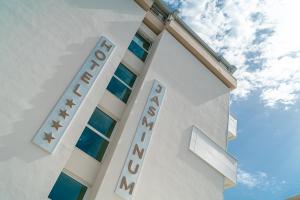 a white building with a hotel sign on it at Hotel Jasminum in Bibione