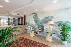 un soggiorno con tavolo in vetro e murale di Hotel Jasminum a Bibione