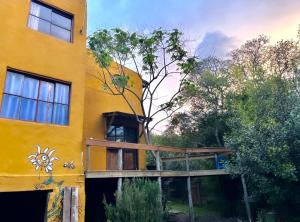 ein gelbes Gebäude mit einer hölzernen Veranda an der Seite in der Unterkunft Habitación con baño privado y cama doble in Piriápolis