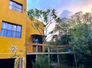 un edificio giallo con un portico di legno sul lato di Habitación con baño privado y cama doble a Piriápolis
