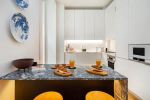 una cocina con mesa y 2 vasos de zumo de naranja en WHome Prime Location Contemporary Luxury Apartment w/ AC & Elevator, en Lisboa