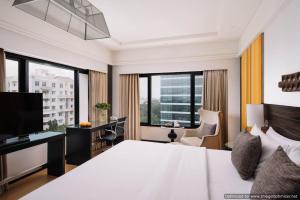 a hotel room with a bed and a desk and windows at The Raintree, St. Mary’s Road in Chennai