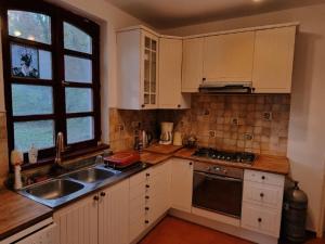 a kitchen with white cabinets and a sink and a window at Never Say Never Vendégház 