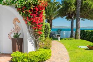 a garden with red flowers on a white wall at The Pelican Beach Resort & SPA - Adults Only in Olbia