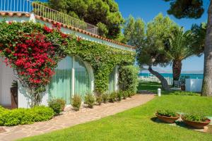 a garden with red flowers and bushes next to a building at The Pelican Beach Resort & SPA - Adults Only in Olbia