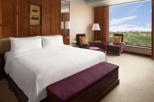 a bedroom with a large bed and a large window at Shangri-La Chiang Mai in Chiang Mai