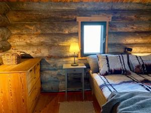 a bedroom with a bed and a table with a window at Tunturikelo - beautiful log cottage in the Fells in Utsjoki