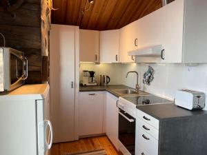 a kitchen with white cabinets and a sink at Tunturikelo - beautiful log cottage in the Fells in Utsjoki