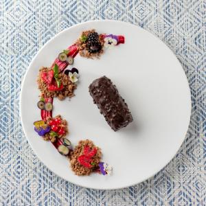 a plate with a piece of chocolate cake and berries at The Pelican Beach Resort & SPA - Adults Only in Olbia