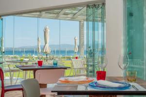 a dining room with a table and chairs with a view of the ocean at The Pelican Beach Resort & SPA - Adults Only in Olbia