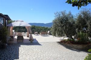 a patio with tables and chairs and an umbrella at Fattoria Cristina - Bilo Verde in Castelnuovo Magra