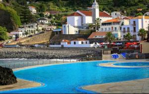 a view of a swimming pool with a town in the background at House pc in Porto da Cruz