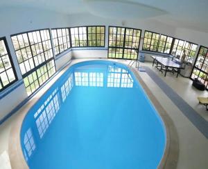 a large swimming pool in a building with windows at House pc in Porto da Cruz