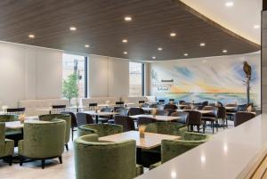 un comedor con mesas y sillas y un mural en Wyndham Garden Winnipeg Airport en Winnipeg