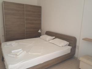a bed with two white pillows and a wooden headboard at Balchik Gardens complex SeaHome 21 apartment in Balchik