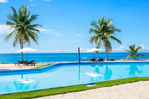 a swimming pool next to the beach with palm trees at Nosy Saba Private Island & Spa in Nosy Saba