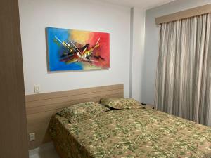 1 dormitorio con 1 cama y una pintura en la pared en Flat 405 - Condomínio Veredas do Rio Quente - Diferenciado com ar na sala e no quarto in 