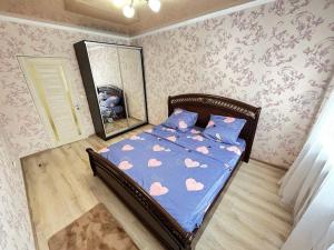 um quarto com uma cama com um espelho e papel de parede rosa em Дом просто Сказка em Atyrau