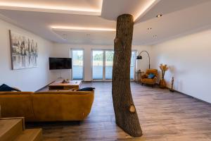 a tree in the middle of a living room with a couch at Ferienpark Harkebrügge Haus Spiekeroog in Barßel