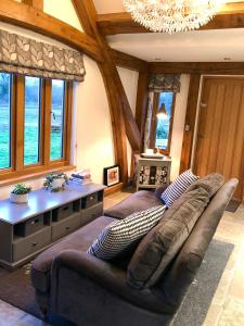 uma sala de estar com um sofá e um lustre em Quality Oak Barn with Hot Tub and Parking em Bramley
