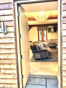 uma sala de estar com um sofá e um lustre em Quality Oak Barn with Hot Tub and Parking em Bramley