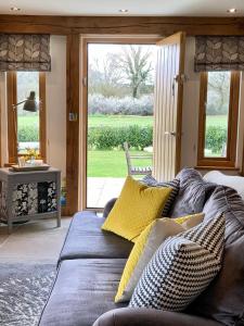 a living room with a couch with yellow pillows at Quality Oak Barn with Hot Tub and Parking in Bramley