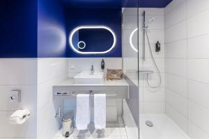 a bathroom with a sink and a shower with a mirror at ibis Styles Muenchen Perlach in Munich