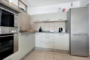 a kitchen with white cabinets and a stainless steel refrigerator at Casa Médano 17 in Granadilla de Abona